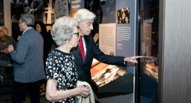 Deux personnes âgées regardant une exposition dans le musée, l'une pointant du doigt.