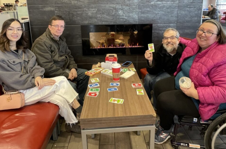 A group of four people playing a game of cards at a local coffee shop.